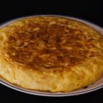 Frittata alta e soffice su un piatto, decorata con erbe fresche, rappresenta il piatto dell'articolo.
