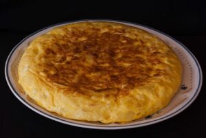 Frittata alta e soffice su un piatto, decorata con erbe fresche, rappresenta il piatto dell'articolo.