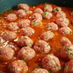 Polpette succulente nel sugo, servite in un piatto rustico con basilico fresco.