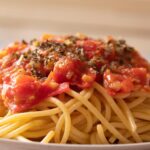 Pasta al pomodoro servita in un piatto, con salsa ricca e profumata, guarnita con basilico fresco.
