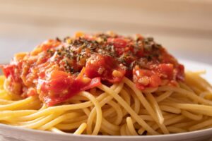 Pasta al pomodoro servita in un piatto, con salsa ricca e profumata, guarnita con basilico fresco.